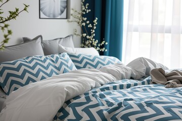 Modern elegant bedroom interior showcases a neatly made bed with blue accents bedding, patterned pillows, and decorative bedside elements. Organic cotton bed linen.