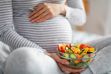Pregnant woman eating healthy salad at home, cropped