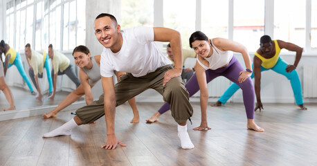 Positive Asian boy engaged in aerobic dance together with other attendees of dancing courses