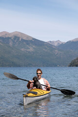 Beautiful young woman enjoys her best companion and friend her pet dog, while kayaking on the lakes of southern Argentina, Bariloche, Patagonia.
