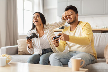 Happy couple playing video games together at home
