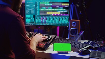 Musical performer creating mixed sounds and tunes with mixing console, greenscreen running on phone...