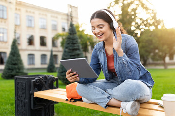 Lady with headphones using tablet and headphones outside