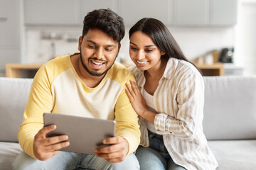Smiling couple using a digital tablet at home