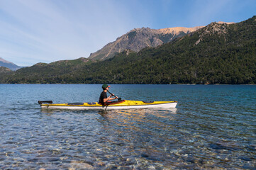 Young teenager practices kayaking and happily enjoys the landscape offered by Argentine Patagonia, Bariloche.