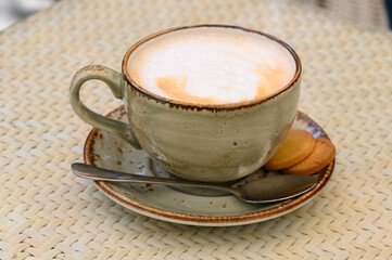 Cup of latte coffee and spoon on gray counter