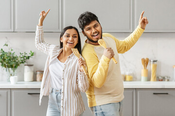 Couple dancing and singing with kitchen utensils