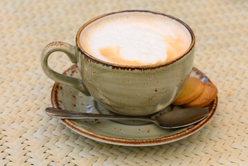 Cup of cappuccino on a table in a cafe. Beautiful foam, white ceramic cup, copy space.