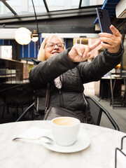 pov senior woman laughing enjoying taking selfie with the cell phone with the coffees already finished - 785760725