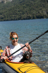 Fototapeta premium Woman enjoying a nice kayak ride with her dog as a companion through the lakes of southern Argentina.