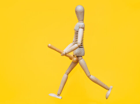 The wooden man is holding a stick in his hands that resembles a large erotic penis and is running after someone. Concept of large size, priapism and strong libido. Sexual maniac.
