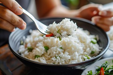 Detailed close-up of a person relishing a forkful of fragrant jasmine rice