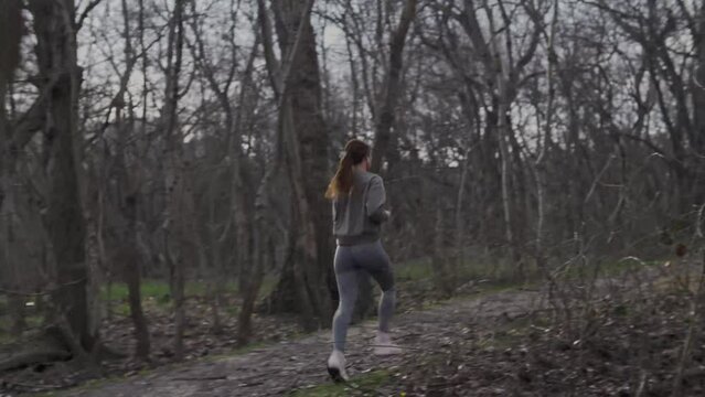 Sporty jogging of an attractive girl in a forest 