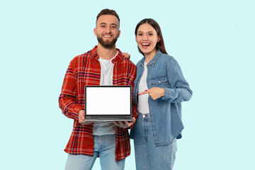 Couple displaying laptop screen to viewer on blue background