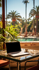 A laptop on a hotel's table, a pool in the background, concept of business travel and remote work concept