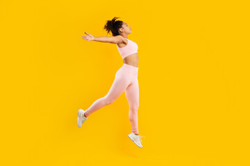 Fototapeta na wymiar Energetic lady jumping in pink fitness attire