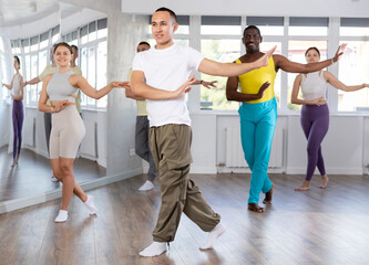 During dance workshop, European guy with team of like-minded multinational people learn to perform...