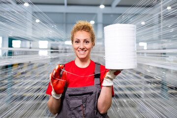 Portrait of female worker holding thread spool in textile factory.