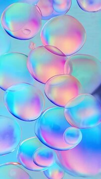 Vibrant holographic background. Transparent oil drops with pastel rainbow colors on blue background