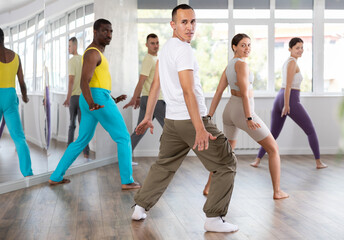 During dance workshop, European guy with team of like-minded multinational people learn to perform elements of energy waacking dance. Studio school for amateur and professional dancers