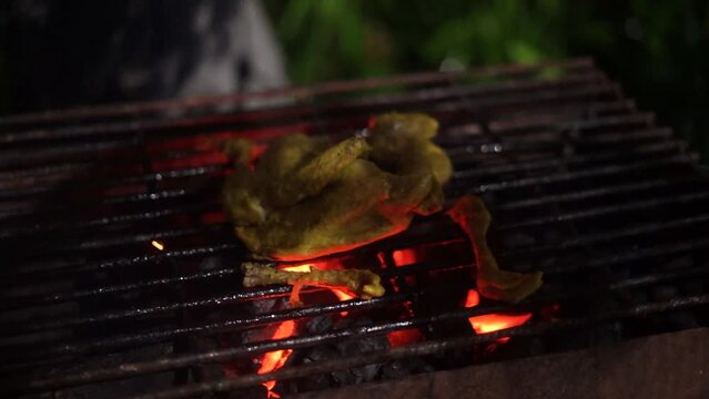 a chicken ready to be grilled in a grill with charcoal embers