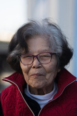 A ninety three year old woman with a splash of gray hair looks at the camera with a coy smile. She...