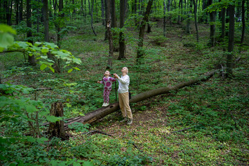 Mother and little girl looking for birds in forest, enjoying time in nature together 