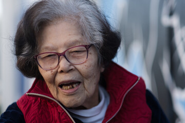 An elderly Asian woman is engaged in a happy, candid conversation. She is over ninety years old,...