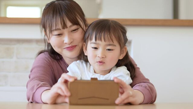 スマートフォンを使う親子　女の子とお母さん