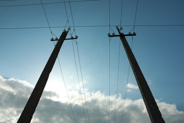 Telephone poles and wires against blue sky with clouds