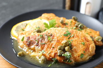 Delicious chicken piccata with herbs on table, closeup