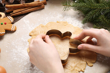 Woman making Christmas cookie with cutter at table, closeup