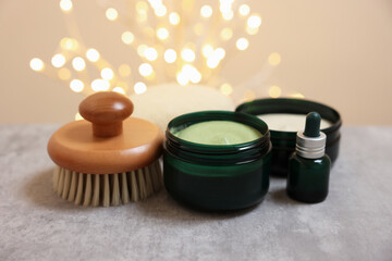Natural scrub and other body care products on grey table against blurred lights