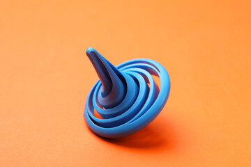 One blue spinning top on orange background, closeup