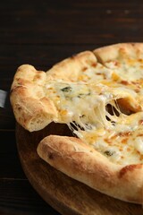 Taking piece of delicious cheese pizza at wooden table, closeup