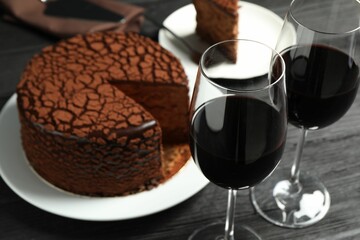 Delicious chocolate truffle cake and red wine on black wooden table