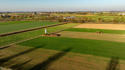 The warm light of the setting sun highlights a patchwork of agricultural fields, presenting a...