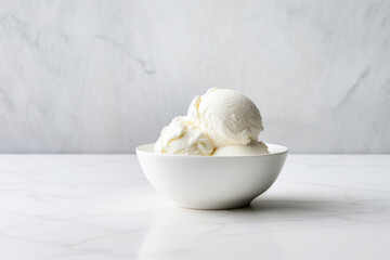 Vanilla ice cream served in a simple white bowl on a marble surface with neutral background
