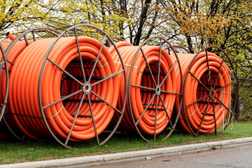 Spools of orange fiber optic cable underground conduit on a mobile reel for fiber optic cable...