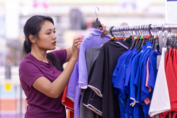 A young woman chooses a t-shirt in a store