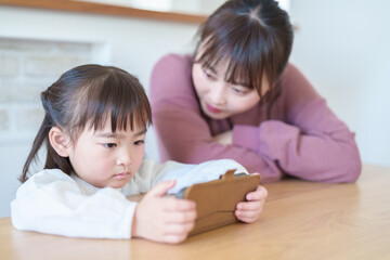 Obraz na płótnie Canvas スマートフォンを使う女の子を見守るお母さん