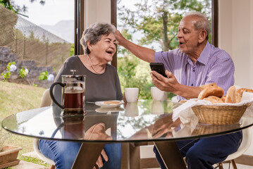 Adult married couple sitting at a table celebrating great news.