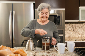 Senior woman making coffee in the kitchen. Using an easy method.