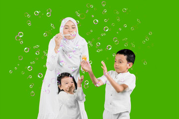Young Muslim mother playing soap bubbles with their children