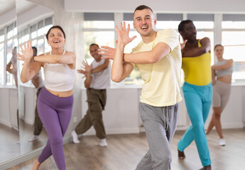 Positive guy engaged in active dance together with other attendees of dancing courses