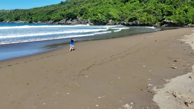 woman walking on tropical sandy beach leaving footprints. Woman tourist on summer vacation on paradise island on tropical beach bali indonesia.