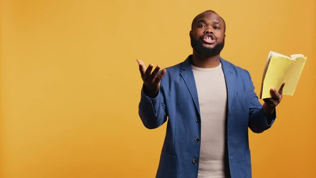 Man reading book aloud, narrating story for audience, doing monologue for theatre play. Person rehearsing using literature novel source material, reciting from pages, studio background, camera B
