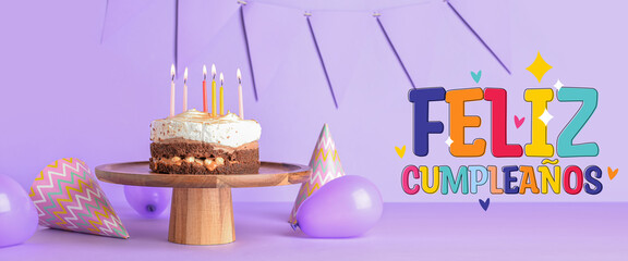 Stand with tasty birthday cake, balloons and party hats on purple background