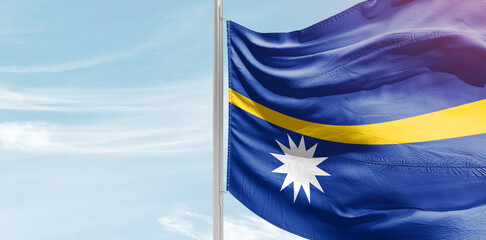 Nauru national flag with mast at light blue sky. - obrazy, fototapety, plakaty