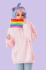 Beautiful young woman with LGBT flag on lilac background
